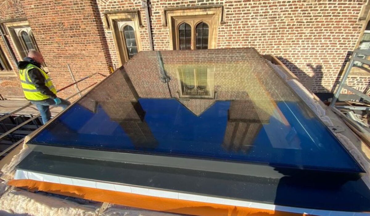 oversized venting rooflight on a roof with a man in a high vis stood to the left of it