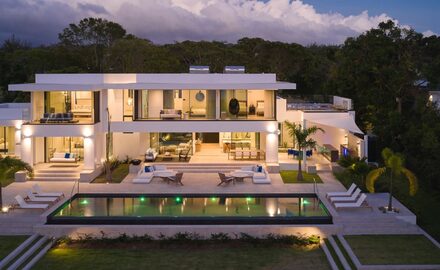 a contemporary house in Barbados with lots of glass shown at night