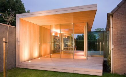 a glass and timber garden room shown at night