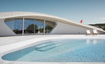 Bespoke curved holiday villa with slim sliding glass doors opening onto outdoor pool