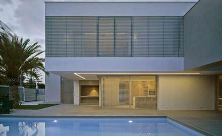 Spanish coastal villa with corner open sliding glass doors leading into outdoor swimming pool
