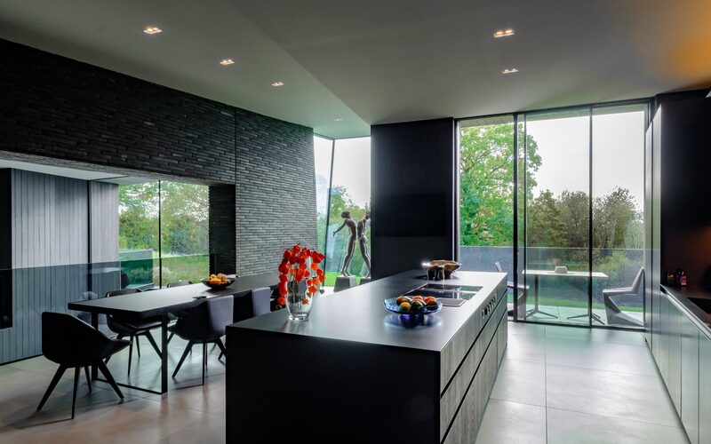 a modern kitchen with dark walls and large windows