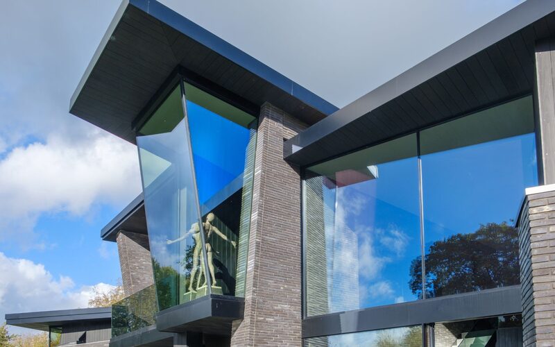 outward leaning frameless structural glass window on a modern house