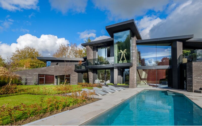 oversized frameless windows on the rear face of a modern house build with an outdoor pool