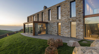 Coastal new build home with glass box extension and frameless picture windows