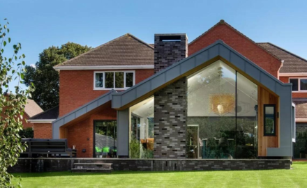 modern extension to a traditional red brick house with a structural glass wall